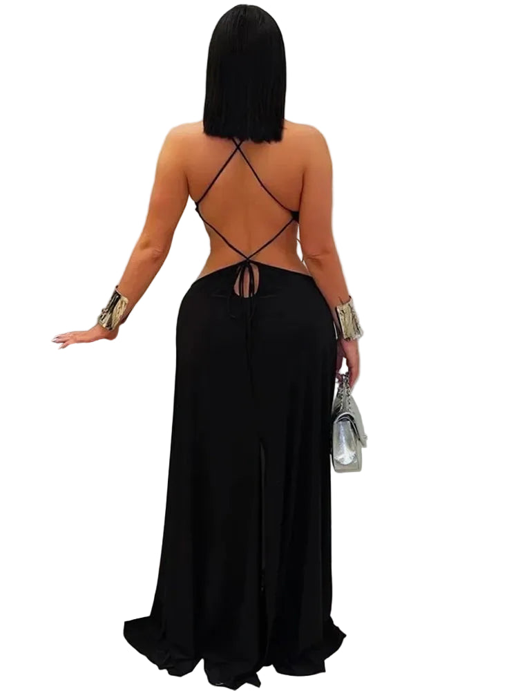 Person wearing a black dress with a unique back design, standing in a minimal indoor setting.
