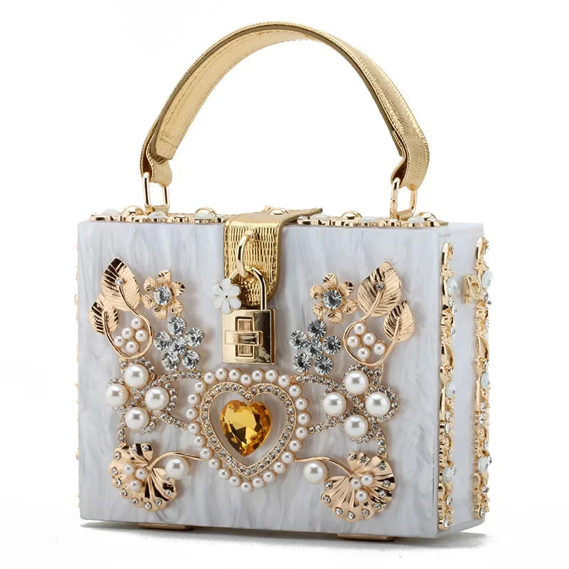 Decorative handbag with gold accents, pearls, and heart design on a white background
