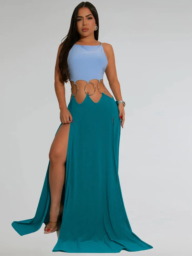 Woman wearing a blue top and teal skirt with a high slit on a gray background